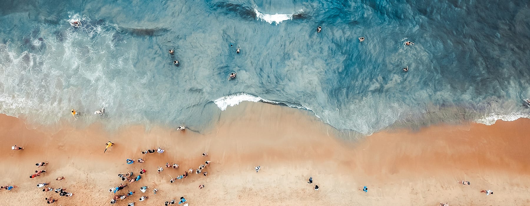 aerial view of a beach showing blue waves and tan sands
