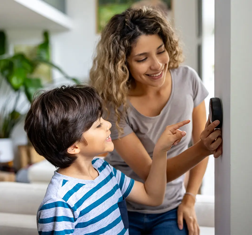 mom and son adjusting the thermostat